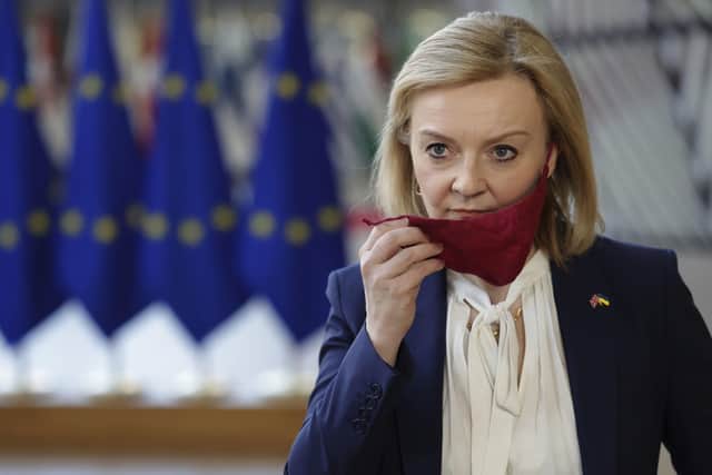 Foreign Secretary Liz Truss takes off her protective face mask as she arrives for an extraordinary EU foreign ministers meeting at the European Council building in Brussels.