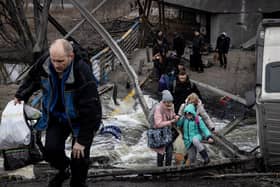 Residents of Irpin flee heavy fighting via a destroyed bridge as Russian forces entered the city on March 07, 2022 in Irpin, Ukraine. (Photo by Chris McGrath/Getty Images)