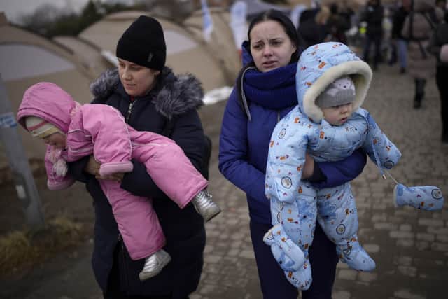 Women carry children after crossing from Ukraine in Medyka, Poland, Wednesday, March 9, 2022. (AP Photo/Daniel Cole).