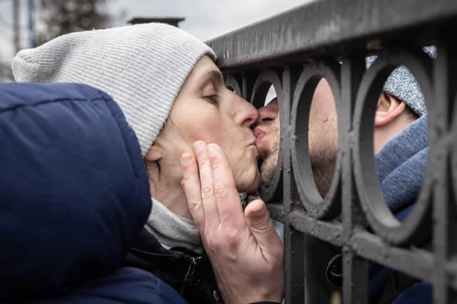 Oleg kisses his wife Yana goodbye through a train platform fence as she waits to board an evacuation train with their eleven month-old son Maksim after fleeing heavy overnight fighting in Bucha and Irpin on March 04, 2022 in Kyiv, Ukraine. Russia continues their assault on Ukraine's major cities, including the capital Kyiv, a week after launching a large-scale invasion of the country. (Photo by Chris McGrath/Getty Images).