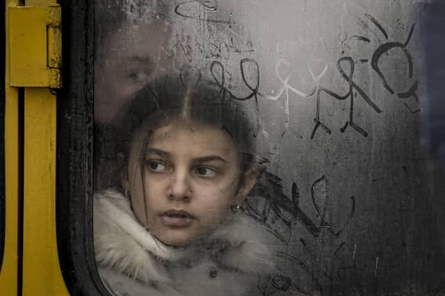 A child looks out a steamy bus window with drawings on it as civilians are evacuated from Irpin, on the outskirts of Kyiv, Ukraine, Wednesday, March 9, 2022. A Russian airstrike devastated a maternity hospital Wednesday in the besieged port city of Mariupol amid growing warnings from the West that Moscow's invasion is about to take a more brutal and indiscriminate turn. (AP Photo/Vadim Ghirda).