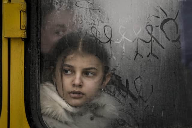 A child looks out a steamy bus window with drawings on it as civilians are evacuated from Irpin, on the outskirts of Kyiv, Ukraine, Wednesday, March 9, 2022. A Russian airstrike devastated a maternity hospital Wednesday in the besieged port city of Mariupol amid growing warnings from the West that Moscow's invasion is about to take a more brutal and indiscriminate turn. (AP Photo/Vadim Ghirda).