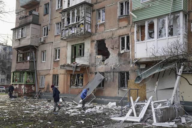 People walk next to an apartment building hit by shelling in Mariupol, Ukraine, Monday, March 7, 2022. 
A hospital in Mariupol has reportedly now been struck, causing severe damage. (AP Photo/Evgeniy Maloletka)