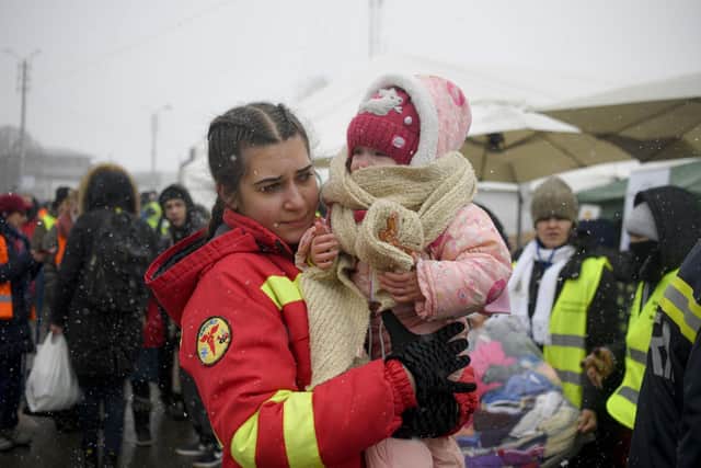 An employee from the Emergency Situations Department holds the baby of a refugee fleeing the conflict from neighbouring Ukraine at the Romanian-Ukrainian border, in Siret, Romania, Thursday, March 10, 2022. (AP Photo/Andreea Alexandru)