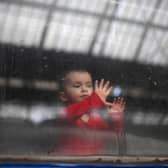 A child looks out from a carriage window as a train prepares to depart from a station in Lviv, western Ukraine, enroute to the town of Uzhhorod near the border with Slovakia, on March 3, 2022. Photo by DANIEL LEAL/AFP via Getty Images.