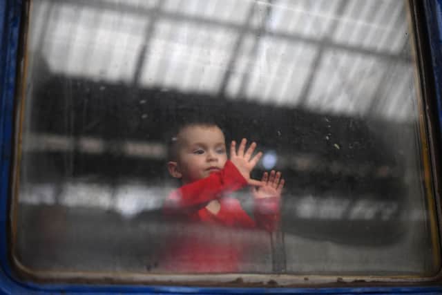 A child looks out from a carriage window as a train prepares to depart from a station in Lviv, western Ukraine, enroute to the town of Uzhhorod near the border with Slovakia, on March 3, 2022. Photo by DANIEL LEAL/AFP via Getty Images.