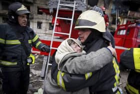 In this photo released by Ukrainian State Emergency Service, a firefighter hugs an elderly woman after evacuation from an apartment building hit by shelling in Kyiv, Ukraine, Monday, March 14, 2022. (Ukrainian State Emergency Service via AP).