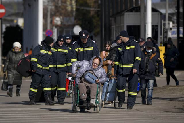 Firefighters help a refugee fleeing the war from neighbouring Ukraine at the Romanian-Ukrainian border, in Siret, Romania, Monday, March 14, 2022. (AP Photo/Andreea Alexandru).