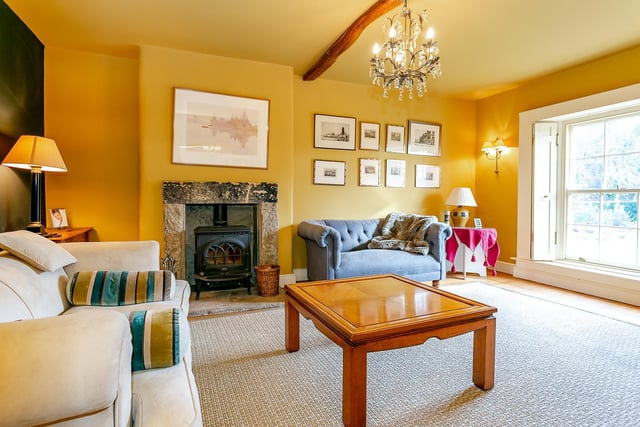 Sun streams in through the windows of the sitting room, which is painted in a uplifting yellow