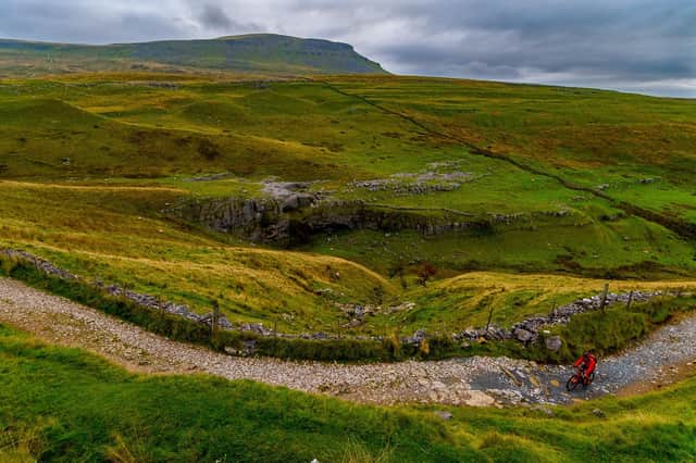 A cyclist takes an early morning ride up a track from the rural village of Horton-In-Ribblesdale in the heart of the Yorkshire Dales with a backdrop of Pen-y-ghent. Picture: James Hardsity.
