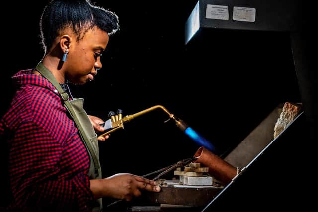 Sheffield sculptor Francisca Onumah using a blowtortch in her studio. She is also wearing her own tube earrings.