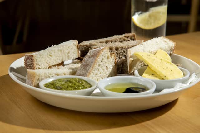 Plate of white and rye sourdough bread smoked seaweed salt butter, olive oil and aged balsamic and green sauce.