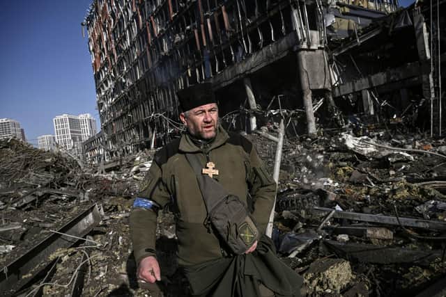 Ukraine army Chaplain Mikola Madenski walks through debris outside the destroyed Retroville shopping mall in a residential district, after a Russian attack on the Ukranian capital Kyiv.