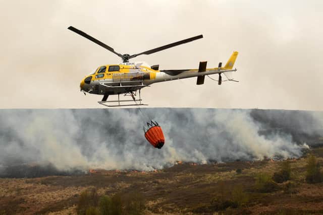 A helicopter drops water onto flames after a resurgence of a moor fire on Marsden Moor, near Huddersfield in April last year. Fifty firefighters were deployed to tackle the blaze with a mile-long flame front.