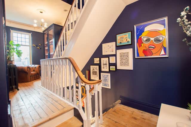 The staircase runs up two storeys and is backed by feature walls with the Cotterells collection of art