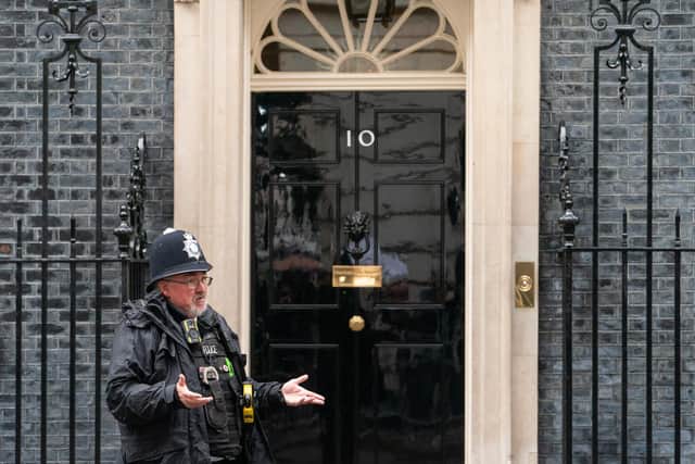 A police officer gestures to colleagues outside 10 Downing Street, in Westminster, London.