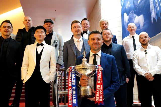 Defending champion Mark Selby (front) with the Betfred World Championship trophy with Mark Allen, Anthony McGill, Luca Brecel, Shaun Murphy, Neil Robertson, Barry Hawkins, Stuart Bingham, Yan Bingtao, Mark Williams, John Higgins, Ronnie O'Sullivan, Kyren Wilson and Zhao Xinong during the media day at the Crucible. Photo: Zac Goodwin/PA Wire.