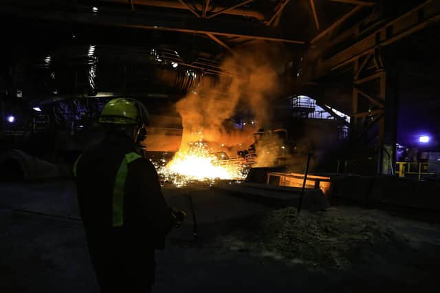 A steelworker watches as molten steel pours from one of the Blast Furnaces during 'tapping' at the British Steel - Scunthorpe. Photo credit: LINDSEY PARNABY/AFP/Getty Images).