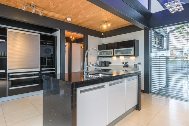 The sleek kitchen with granite worksurfaces, two integrated Miele ovens, a five ring induction hob with extractor, dishwasher, fridge and freezer. The matching island unit has an overhanging breakfast bar and an inset sink unit with mixer tap.