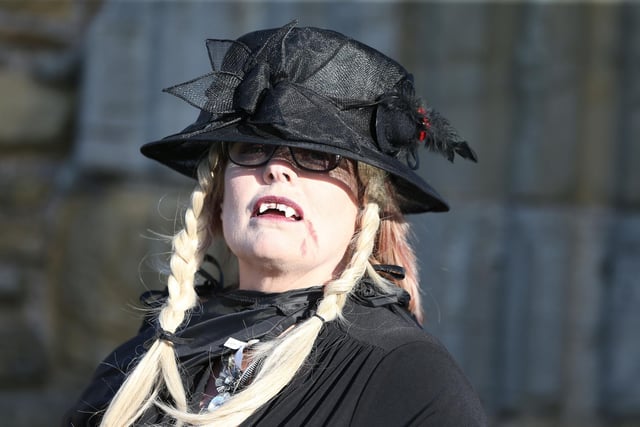 A woman wears a black hat and fangs to attend the record attempt
