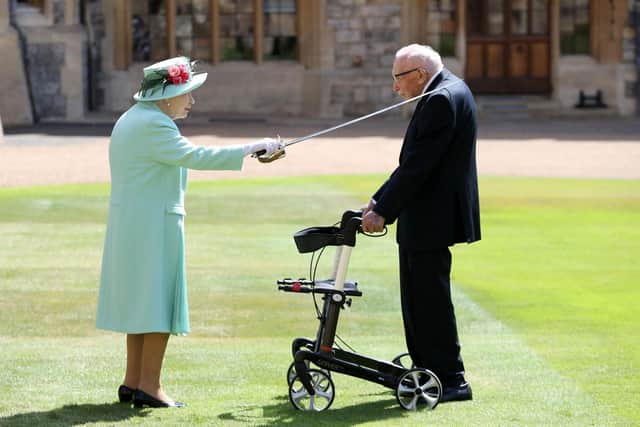 TOPSHOT - Britain's Queen Elizabeth II uses the sword that belonged to her father, George VI as she confers the Honour of Knighthood on 100-year-old veteran Captain Tom Moore at Windsor Castle in Windsor, west of London on July 17, 2020. - British World War II veteran Captain Tom Moore was made a a Knight Bachelor (Knighthood) for raising over £32 million for the NHS during the coronavirus pandemic. (Photo by Chris Jackson / POOL / AFP) (Photo by CHRIS JACKSON/POOL/AFP via Getty Images)