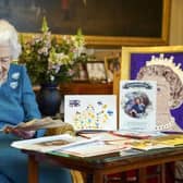Queen Elizabeth II looks at a fan as she views a display of memorabilia from her Golden and Platinum Jubilees in the Oak Room at Windsor Castle.