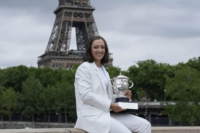 Poland's Iga Swiatek poses with the trophy on Bir-Hakeim bridge as the Eiffel Tower is seen in the background in Paris, France, Sunday, June 5, 2022, after she won Saturday's women's final match at the French Open tennis tournament in Roland Garros stadium. (AP Photo/Christophe Ena)