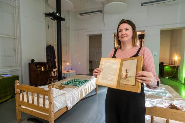 Claire Duffield, Senior Librarian for Audience Development at Leeds Central Libray, holding the Princess Mary's Gift Book, where it's believed the cousins got the idea from before photographing themselves in their garden