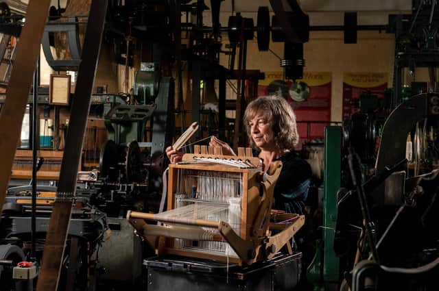Anne Bardsley with her small loom among the historic looms at Bradford Industrial Museum