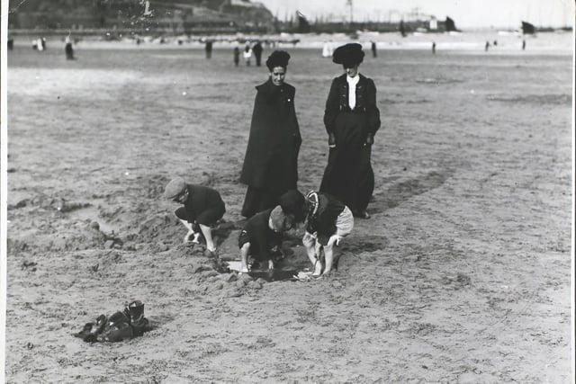 Two women watching children at play, digging on the beach on Scarborough sands, England, 1907. (Photo by Topical Press Agency/Hulton Archive/Getty Images)