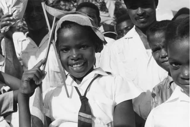 August 1962:  A Jamaican schoolgirl in Kingston with the country's new flag during Jamaica's independence celebrations.  Photo by George Freston/Fox Photos/Getty Images