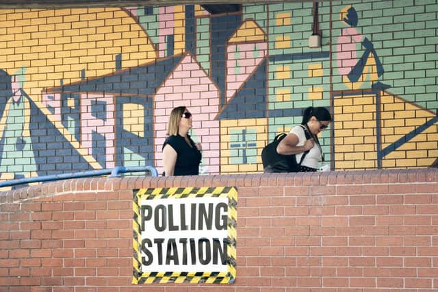 People wall past polling sign at Lightwaves Leisure Centre in Wakefield, West Yorkshire, during the Wakefield by-election