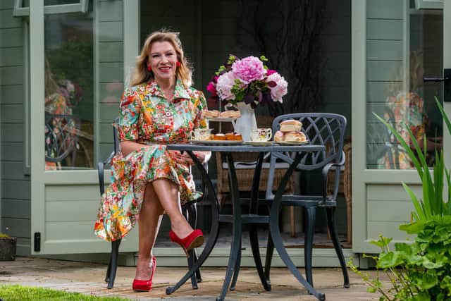 In the garden of her friends and neighbours Harriet and Tom, Amanda wears a vintafe floral-print 1960s buttoned dress.