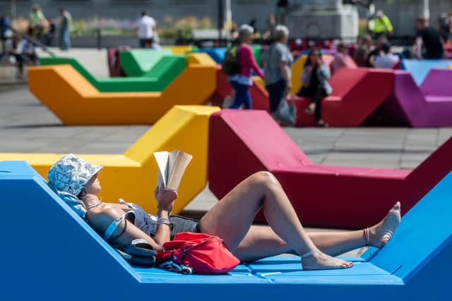 A sunbather relaxes on the colourful urban benches positioned in Victoria Gardens, Leeds, in front of the Art Gallery on July 7 [Photo: James Hardisty]