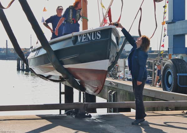 Julie Coultas names the recently restored sailing coble Venus with a bottle of rum. Photo courtesy of Paul L Arro