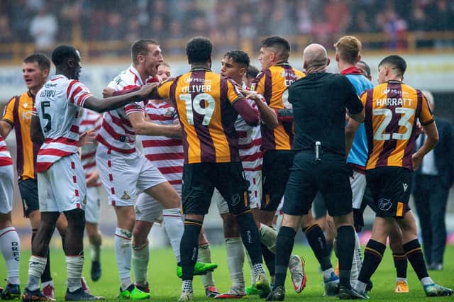 Flare up: Referee Robert Madden tries to sort out a fracas betweeen Bradford and Doncaster players at the final whistle. Picture: Bruce Rollinson