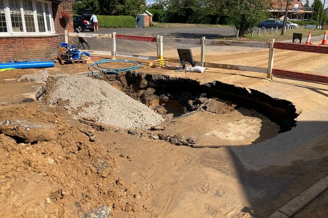 The damage to the road caused by the sinkhole.