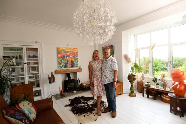 Rob and Alison in the sitting room with a painting by Claire West above the firelace