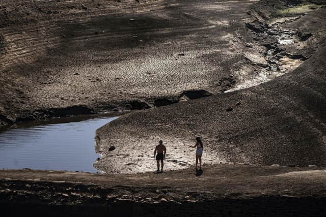 People walk on the dry cracked earth at Baitings Reservoir in Ripponden, West Yorkshire, where water levels are significantly low. Credit: Danny Lawson/PA Wire