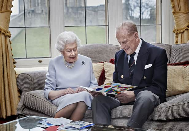 A touching photo of the Queen and Prince Philip on their 73rd wedding anniversary as they open a card from the Duke and Duchess of Cambridge's three children.