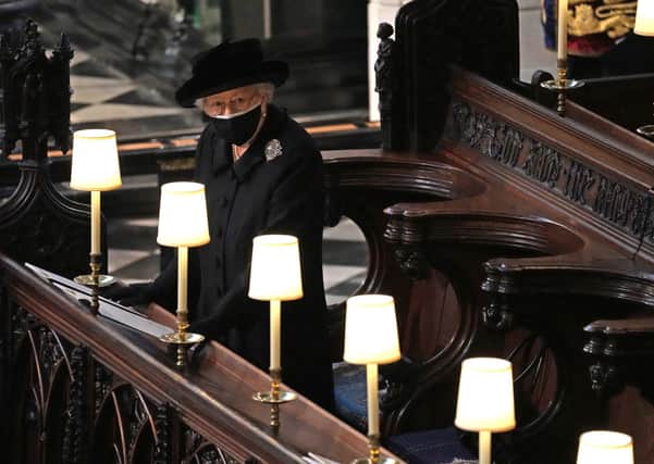 A heartbreaking photo of the Queen as she watches pallbearers carry Prince Philip's coffin through St George's Chapel during his funeral.