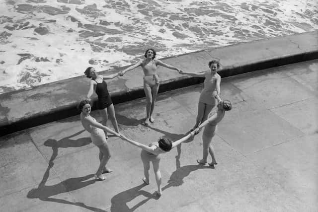 June 1936:  Bathing belles form a circle on the water's edge at Scarborough, North Yorkshire.  (Photo by Fox Photos/Getty Images)