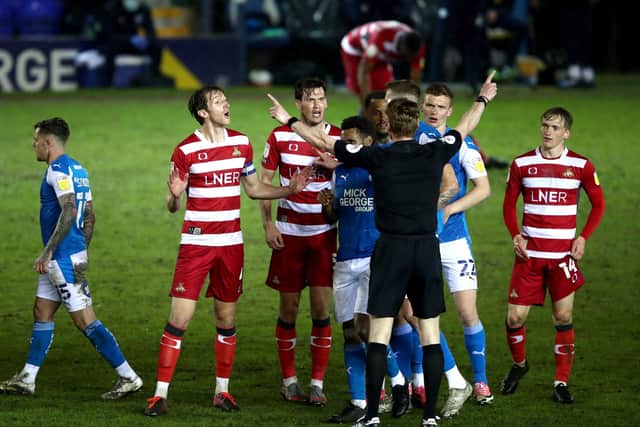 Peterborough United and Doncaster Rovers players surround referee Scott Oldham. Picture: PA