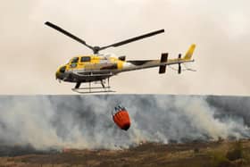 A helicopter drops water from a local reservoir on the fire at Marsden Moor, which burned for three days in April