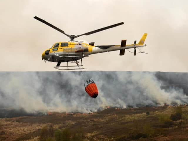 A helicopter drops water from a local reservoir on the fire at Marsden Moor, which burned for three days in April