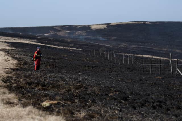 A firefighter monitors any resurgence of a moor fire on Marsden Moor, near Huddersfield.