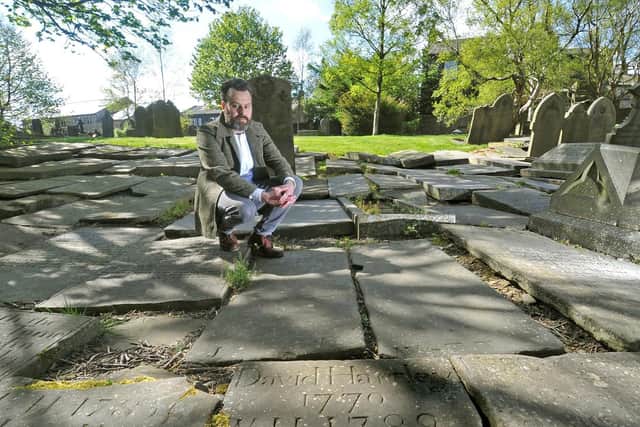 Benjamin Myers at the grave of King David Hartley, leader of the Cragg Vale Coiners buried in the grounds of St Thomas a Becket church in Heptonstall. Picture: Tony Johnson
