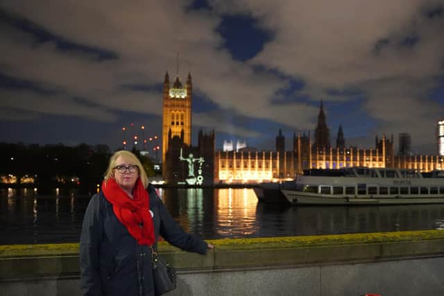 Mo Lea, 61, from Bedford, standing in front of her animation of Lady Justice being projected onto the Houses of Parliament
