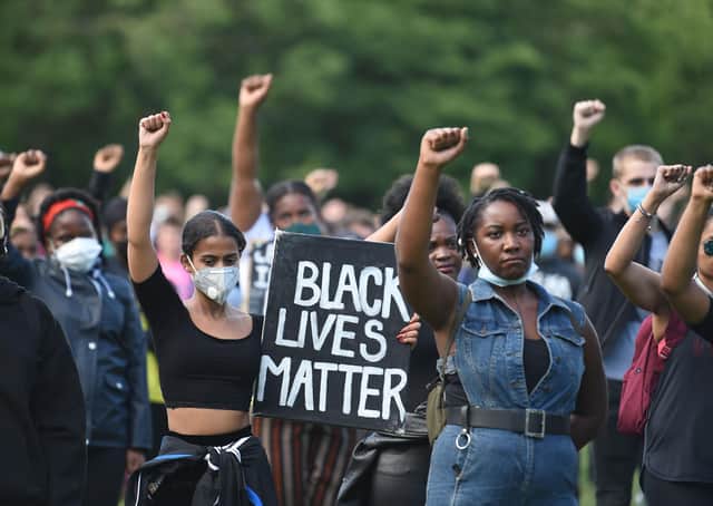Protesters hold up fists at a gathering in support of the Black Lives Matter movement on Woodhouse Moor in Leeds in northern England on June 21, 2020, in the aftermath of the death of unarmed black man George Floyd in police custody in the US. (Photo by Oli SCARFF / AFP)