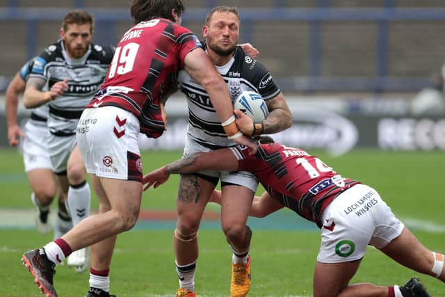 Hull FC's Josh Griffin (centre) tackled by Wigan Warriors' Liam Byrne (left) and Oliver Partington (right).